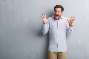 Yakışıklı genç iş adamı gri grunge üzerinde duvar giyen şık gömlek deli kutluyor ve crazy arms ile başarı için kaldırdı ve heyecanlı çığlık gözler kapalı. Kazanan kavramı