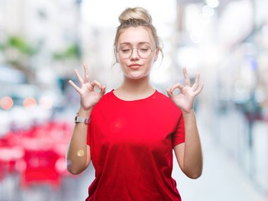 Sarışın genç kadın gözlük izole arka plan üzerinde dinlenmek ve gülümseyen gözlerle kapalı parmak jestle meditasyon yapıyor. Yoga kavramı.