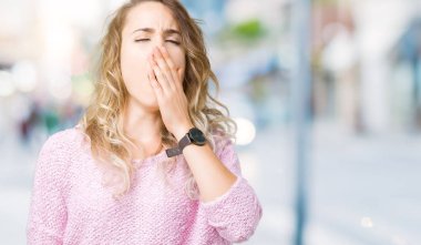 Güzel genç sarışın kadın izole arka plan üzerinde el ile ağız kapsayan yorgun esneme sıkılmış. Restless ve uyku hali.