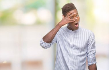 Genç Afro-Amerikan adam utanç ifadesi ile parmaklarımın arasından bakan yüz ve gözler el ile kapsayan şok bakmak izole arka plan üzerinde.