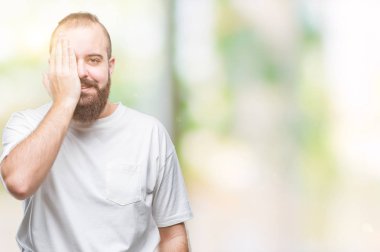 Üzerinde rahat t-shirt giyen genç beyaz hipster adam arka plan kapsayan bir göz yüz ve sürpriz duygu kendinden emin gülümseme ile el ile izole.