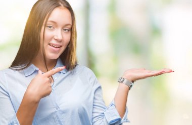 Hayret ve el ile sunulması ve parmak ile işaret ederken kameraya gülümseyen izole arka plan üzerinde beyaz genç güzel kadın.