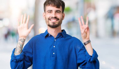 Yakışıklı delikanlı gösterilen ve parmakları ile işaret izole arka plan üzerinde kendinden emin ve mutlu gülümseyerek süre sekiz numara.