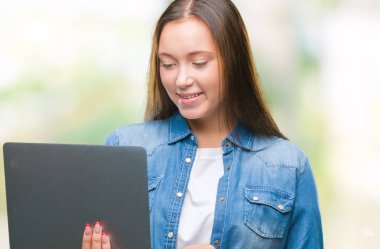 Ayakta ve diş gösterilen kendine güvenen bir gülümsemeyle gülümseyerek mutlu bir yüz ile izole arka plan üzerinde dizüstü bilgisayar kullanan genç beyaz kadın