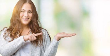 Artı boyutu genç kadın güzel kış ceket üzerinden hayran ve el ile sunulması ve parmak ile işaret ederken kameraya gülümseyen arka plan izole.