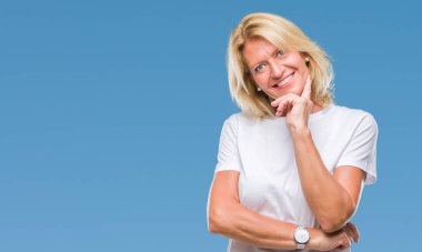 Orta yaş sarışın kadın izole arka plan emin çapraz kollar ve çeneme kaldırdı el ile gülümseme ile kameraya bakıyor. Pozitif düşünce.