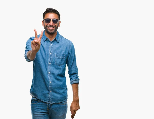 成人拉美裔男子戴着太阳镜在孤立的背景微笑着快乐的脸眨眼在相机做胜利标志 第二个 — 图库照片