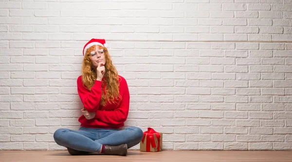 Young Redhead Woman Sitting Brick Wall Wearing Christmas Hat Looking — Stock Photo, Image
