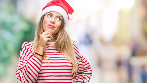若い美しい女性のあごを考えて質問 物思いにふける式の手で隔離された背景にクリスマス帽子をかぶっています 思いやりのある顔をして笑っています 疑いのコンセプト — ストック写真