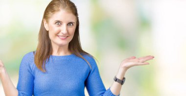 Üzerinde kış kazak giyen güzel orta yaş Olgun kadın arka plan clueless ve şaşkın bir ifadeyle kollar ve eller kaldırdı izole. Şüphe kavramı.