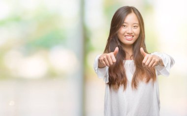 Genç Asyalı kadın el ile pozitif jest yapıyor onaylama izole arka plan üzerinde başparmak gülümseyen ve başarı için mutlu. Kamera, kazanan jest arıyorsunuz.