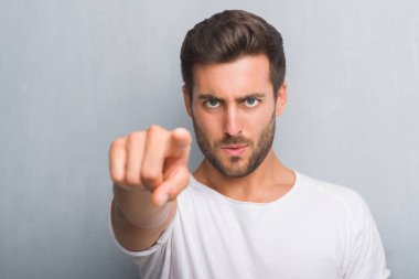Kamera ve size parmak ile işaret gri grunge duvarın üzerinden yakışıklı genç adam, el işareti, pozitif ve kendinden emin bir jest ön