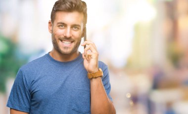 Yakışıklı delikanlı Smartphone'da izole arka plan üzerinde duran ve diş gösterilen kendine güvenen bir gülümsemeyle gülümseyerek mutlu bir yüz ile konuşurken