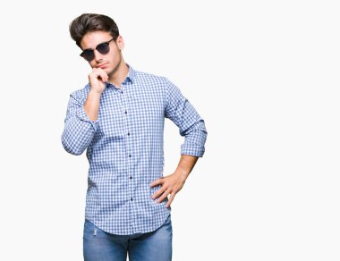 Genç yakışıklı adam çene düşünme hakkında soru, dalgın ifade üzerine el ile izole arka plan üzerinde güneş gözlüğü takıyor. Düşünceli yüzüyle gülümsüyor. Şüphe kavramı.