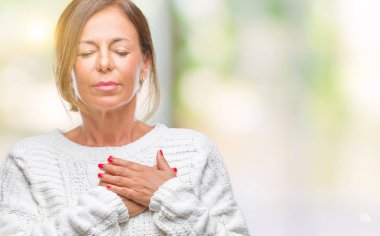 Orta yaş İspanyol kadın kıdemli giyen kış kazak izole arka plan ile gülümseyen üzerinde kapalı gözler ve yüzünde minnettar jest ile göğüs üzerinde eller. Sağlık kavramı.