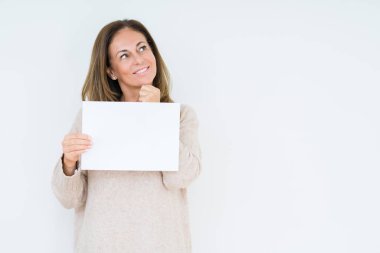 Orta yaş kadın holding boş kağıt sayfası izole arka plan ciddi bir yüz düşünme hakkında soru, çok karışık bir fikir üzerinde