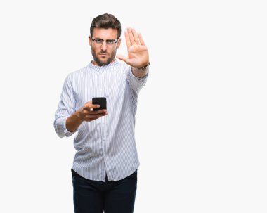 Açık eliyle dur işareti ile ciddi ve kendine güvenen ifade, savunma jest yapıyor izole arka plan üzerinde Smartphone kullanarak yakışıklı delikanlı manifatura
