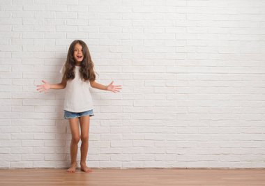 Genç İspanyol çocuğun stading üzerinde beyaz tuğla duvar deli ve çığlık kaldırdı ve açık gözleri heyecanlı silah ile başarı için hayran kutluyor. Kazanan kavramı
