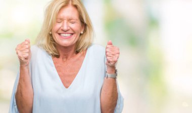 Orta yaş sarışın iş kadını izole arka kolları olan başarı için heyecan üzerinde zafer kutluyor gülümseyen kaldırdı. Kazanan kavramı.