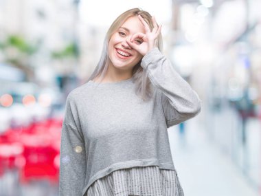 Sarışın genç kadın gülümsüyor, parmakları ile mutlu yüz üzerinden seyir göz el ile ok jest yapıyor izole arka plan üzerinde.