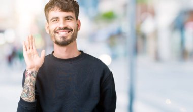 Yakışıklı delikanlı izole arka plan Waiving mutlu selam söyleyerek üzerinde ve gülümseyen, dostça karşılama jest