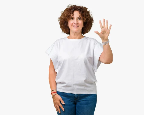 美丽的中间的高级妇女穿着白色 T恤在孤立的背景显示和手指指向五 同时微笑着自信和快乐 — 图库照片