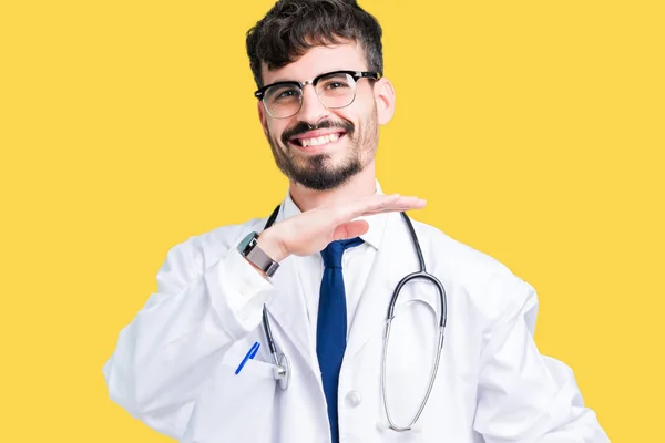 年轻的医生穿在孤立的背景上的医院外套 用手示意大大尺寸的标志 测量符号 看着镜头微笑 测量概念 — 图库照片