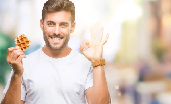 Joven Hombre Guapo Comiendo Dulce Waffle Sobre Fondo Aislado Haciendo —  Fotos de Stock