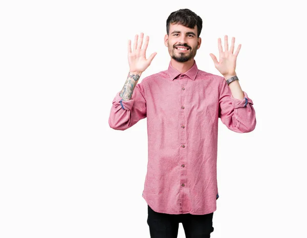 分離背景表示と指で上向きにピンクのシャツを着ている若いハンサムな男は自信を持って 幸せな笑みを浮かべている間 番号します — ストック写真