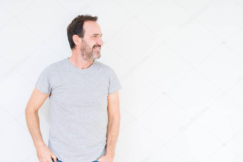 Handsome senior man over isolated background looking away to side with smile on face, natural expression. Laughing confident.