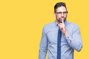 Dudaklarında parmak ile sessiz olmanı izole arka plan üzerinde gözlük takan genç iş adamı. Sessizlik ve gizli kavramı.