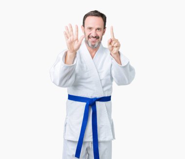 Yakışıklı orta yaş komuta sizde kimono üniforması üzerinde gösterilen arka plan izole ve parmakları ile işaret kendinden emin ve mutlu gülümseyerek süre 6 numara.