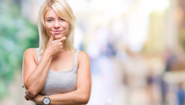 Genç güzel sarışın kadın izole arka plan emin çapraz kollar ve çeneme kaldırdı el ile gülümseme ile kameraya bakıyor. Pozitif düşünce.