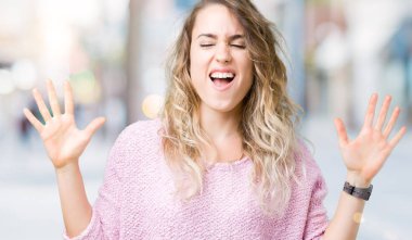 Kızgın ve silah ile başarı için deli kutluyor izole arka plan üzerinde sarışın güzel genç kadın kaldırdı ve heyecanlı çığlık gözler kapalı. Kazanan kavramı