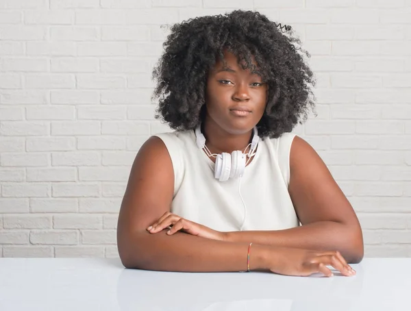 Unga Afroamerikanska Kvinnan Sitter Bord Bär Hörlurar Med Allvarliga Uttryck — Stockfoto