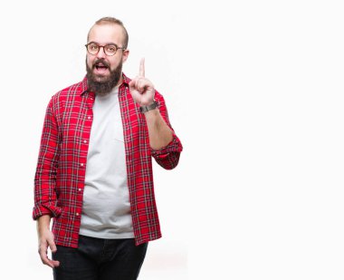 Başarılı fikirle izole arka plan işaret parmağı üzerinde gözlük takan Genç beyaz hipster adam. Çıktıktan ve mutlu. Bir numara.