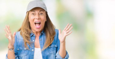 Güzel orta yaş kadın giyiyor spor deli kutluyor izole arka plan üzerinde kap ve başarı için kaldırdı kollarını açarak hayret ve heyecanlı çığlık gözleri açık. Kazanan kavramı