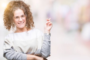 Kameraya bakarak yan el ve parmak ile işaret yüzünde kocaman bir gülümseme ile izole arka plan üzerinde gözlük güzel esmer kıvırcık saçlı Genç kız.
