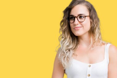 Uzak tarafına yüzünde, doğal ifade gülümseme ile seyir izole arka plan üzerinde gözlük güzel sarışın genç kadın. Kendine güvenen gülüyor.