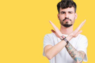 İzole arka plan ret ifade geçiş kollarına eksi işareti, kızgın surat yapıyor beyaz t-shirt giyen genç yakışıklı adam
