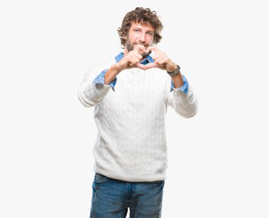 Yakışıklı İspanyol adam aşık kalp simgesi ve elleriyle şekil gösteren gülümseyen izole arka plan üzerinde giyen kış kazak modeli. Romantik kavramı.