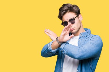 Yakışıklı delikanlı izole arka plan ret ifade geçiş kollarına eksi işareti, kızgın surat yapıyor güneş gözlüğü takıyor