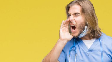 Bağırarak ve ağzı üzerinde el ile yan için çığlık izole arka plan üzerinde uzun saçlı Genç yakışıklı Doktor adam. İletişim kavramı.