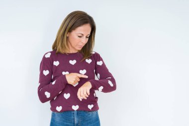 Kol saati, rahat ve kendinden emin zamanında kontrol izole arka plan üzerinde kalp kazak giyen güzel orta yaş kadın