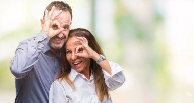 Orta yaş İspanyol iş çift el gülümseyen, ok jest yapıyor izole arka plan üzerinde göz parmakları ile mutlu yüz üzerinden seyir.