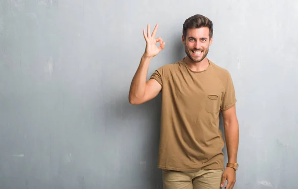 Guapo Joven Sobre Gris Pared Grunge Sonriendo Positiva Haciendo Signo —  Fotos de Stock