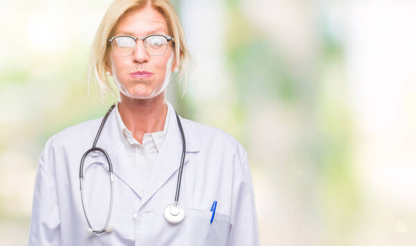 Блондинка средних лет доктор женщина на изолированном фоне пыхтя щеки с забавным лицом. Рот, надутый воздухом, безумное выражение
.