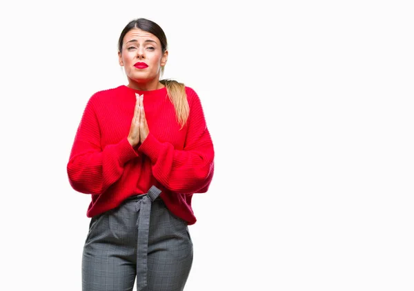 Young beautiful business woman wearing winter sweater over isolated background begging and praying with hands together with hope expression on face very emotional and worried. Asking for forgiveness. Religion concept.