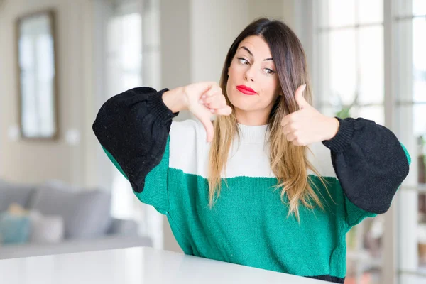 冬のセーターを着て家で若くてきれいな女性は 不一致 契約式の親指をやっています クレイジー衝突 — ストック写真
