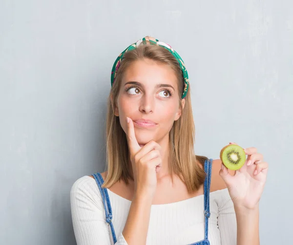 Schöne Junge Frau Über Grunge Graue Wand Essen Frische Kiwi — Stockfoto